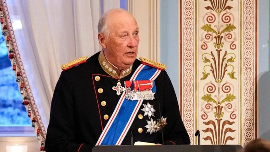 Older man in a dark ceremonial military uniform with gold epaulettes and medals at a podium in a richly decorated room, speaking.