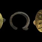 Three archaeological artifacts on a black background: a gold ring with decorative band partly encrusted in dark material, a rusted metal ring fragment in the center, and a gold coin half-buried in dark crust on the right.