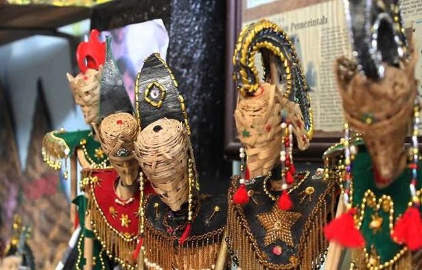 Colorful woven straw puppets with beaded outfits and tassels on display at a market stall.