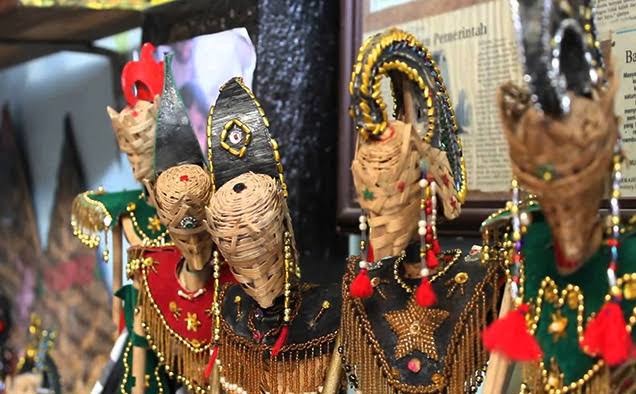 Colorful woven straw puppets with beaded outfits and tassels on display at a market stall.