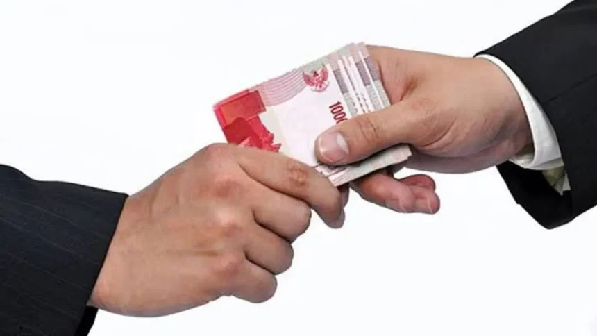 Two hands exchanging a stack of 100,000 Indonesian rupiah banknotes in a cash handoff.