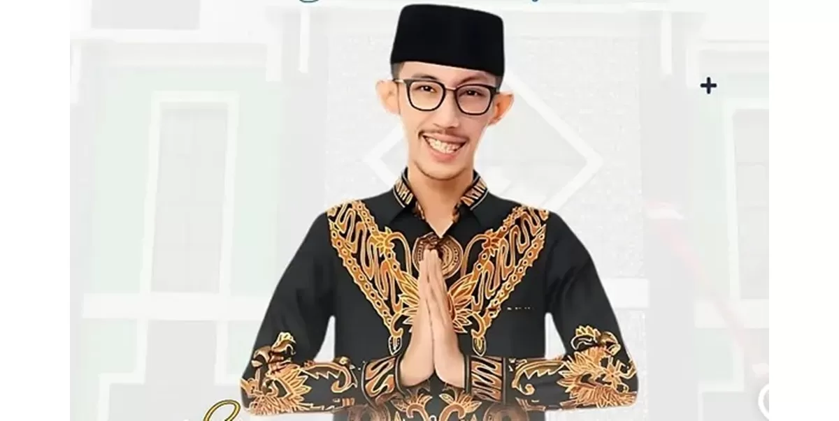 Man in a black batik shirt with gold embroidery, hands in prayer position and smiling at the camera.