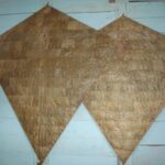 Two large brown diamond-shaped kite wings hanging on a light blue wall.