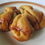 Golden brown fried dough twists on a white plate with a brown rim, crispy exterior.
