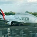 Emirates Airbus A380 on the tarmac receiving a water salute from airport fire trucks."