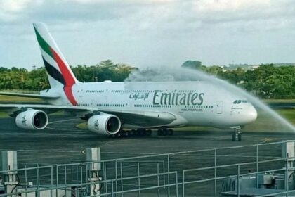 Emirates Airbus A380 on the tarmac receiving a water salute from airport fire trucks."