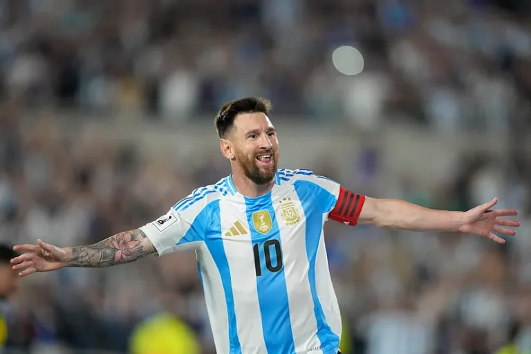 Argentinian soccer captain in a blue-and-white jersey with number 10 celebrates with arms outstretched on the pitch.