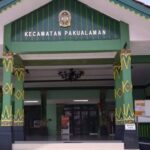 Front entrance of the Kecamatan Pakualaman government building, with green and yellow decorative columns and a sign above the doorway nose.