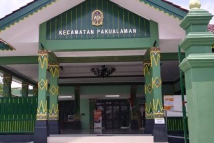 Front entrance of the Kecamatan Pakualaman government building, with green and yellow decorative columns and a sign above the doorway nose.
