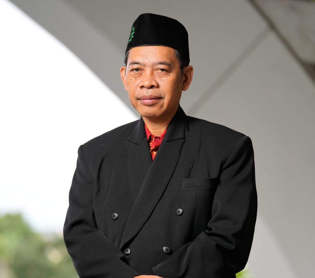29ad44db-f311-4850-a863-692de4e4b492 - Mabur.co Man wearing a black suit and fez, arms crossed, looking at the camera outdoors.