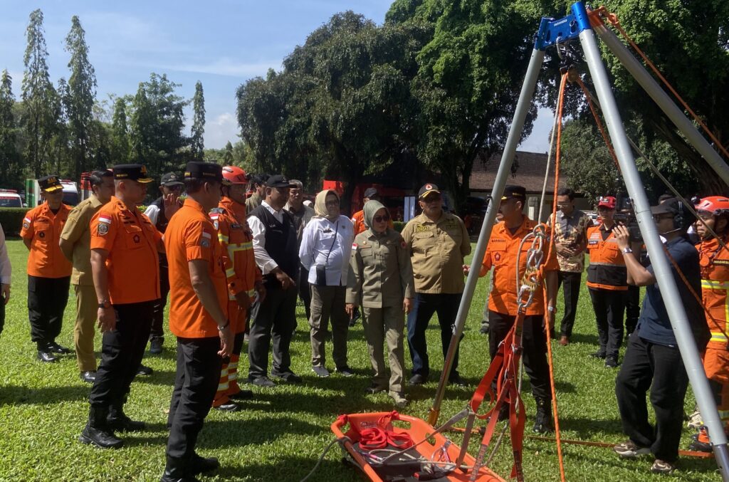 32edwxsz - Mabur.co Group of emergency responders in orange uniforms and tan uniforms watching a drill with lifting gear in a park.