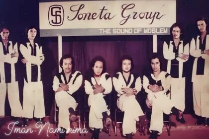 Nine-member band posing on a stage in matching white outfits with black trim; banner above reads 'Soneta Group' and subtitle 'The Sound of ...' as they sit and stand in a row.