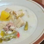 Creamy white soup in a bowl with pork chunks, yellow bell pepper, and mixed vegetables