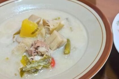 Creamy white soup in a bowl with pork chunks, yellow bell pepper, and mixed vegetables
