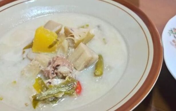 Creamy white soup in a bowl with pork chunks, yellow bell pepper, and mixed vegetables