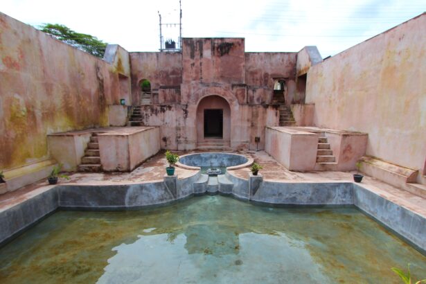 Pink stucco fort courtyard with staircases on both sides, arches, and a central circular fountain surrounded by a shallow pool.