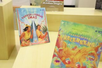 Colorful children's books on a wooden display; left book titled 'Rahasia Si Kembar Emas' shows two kids against a decorative backdrop.