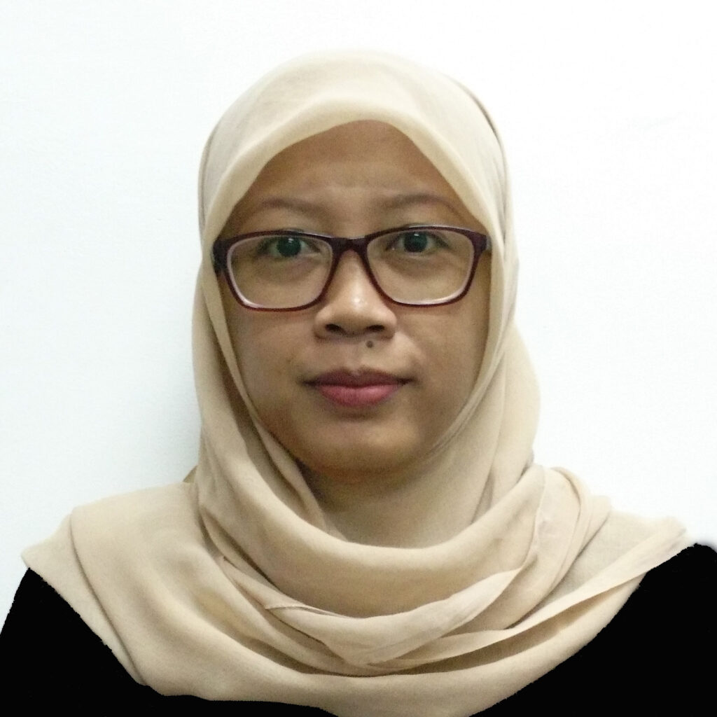 Close-up portrait of a woman wearing a beige hijab and brown-framed glasses, facing the camera.