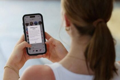 Woman with a ponytail holding a smartphone; the screen shows a messaging notification or chat thread with text visible on the display.