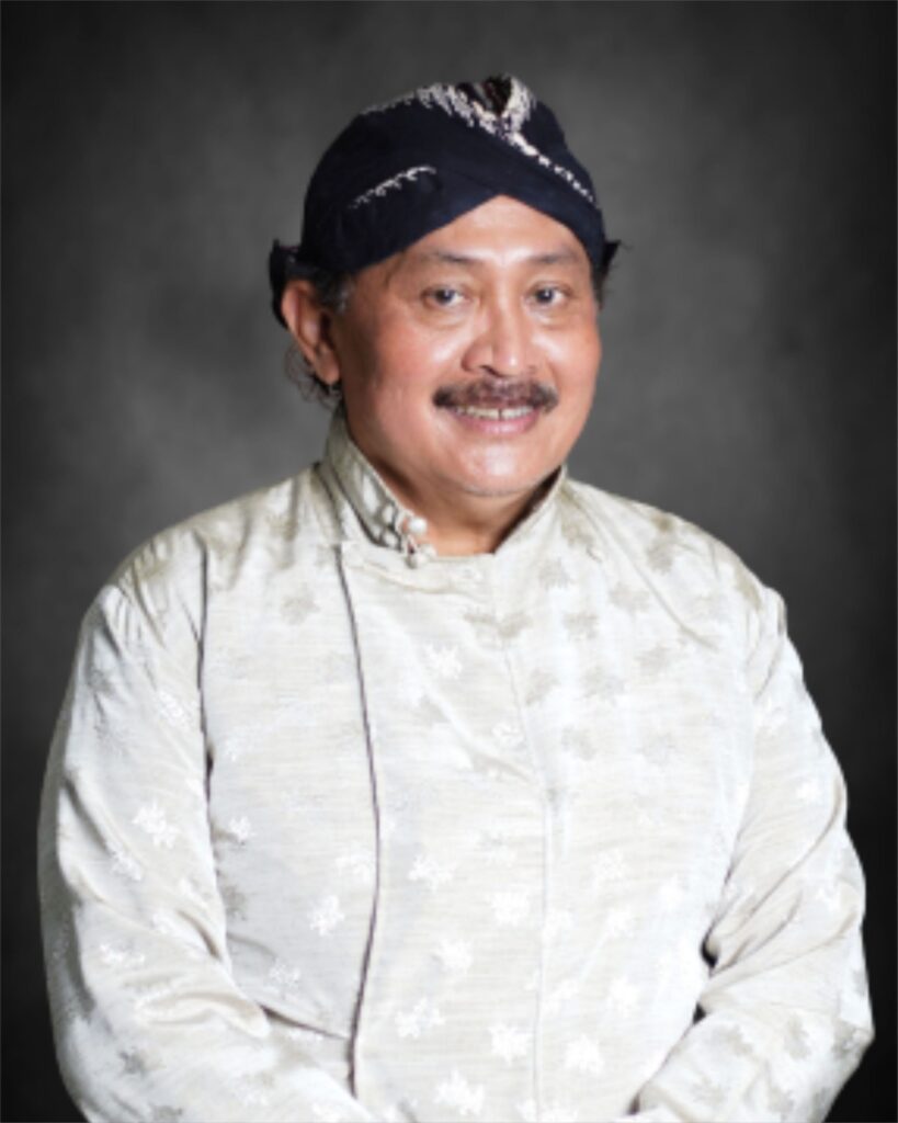 8ASCA - Mabur.co Man wearing a dark turban and light traditional kurta, smiling at the camera against a gray backdrop.