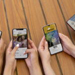 Five hands hold smartphones over a wooden table, displaying a cafe menu, social feed, a DJ party ticket, and a music app interface. Includes café, social, tickets, and music contexts in one scene.