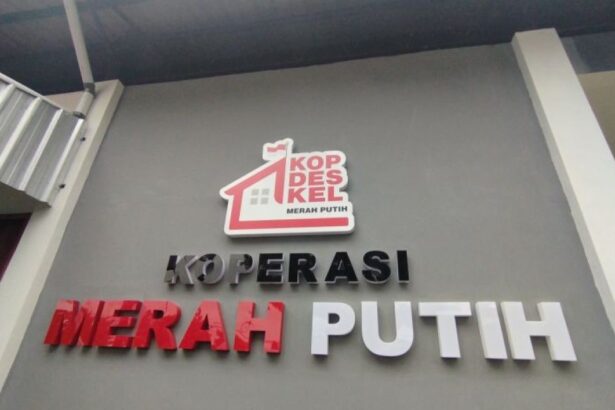 Sign reading KOPERASI MERAH PUTIH with a red roof logo above the text, on a gray wall.