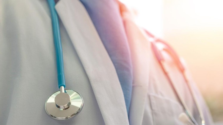 Close-up of a healthcare professional's chest with a blue stethoscope draped around the neck.