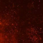 Abstract scene of red-orange sparks and glowing embers against a dark background.
