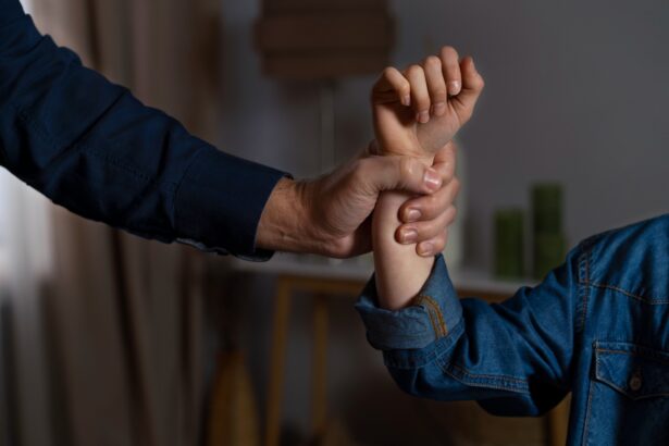 Two people hold each other’s wrists in a firm grip, close-up on their hands against a blurred background.