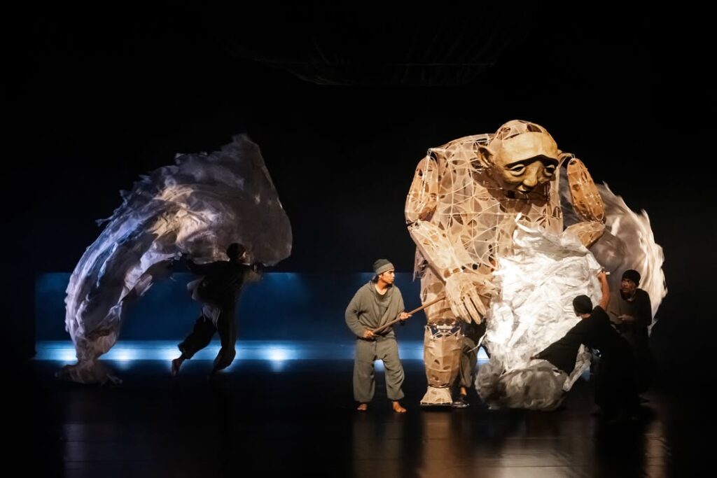 Another Journey with papermoonpuppet Stream of Memory19-20 June 2026Opernhaus Chemnitz Germany 1 - Mabur.co Stage performance featuring a tall giant puppet made of geometric paper strands, surrounded by dancers and billowing white fabric pieces.