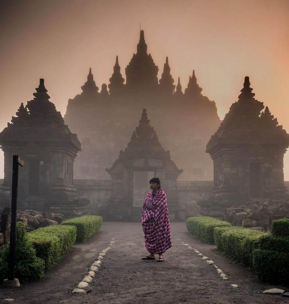Bbbeeerrrrrr Dingin Inframe -eka_kurniawijaya -Taken Using Haida Filter Sy - Mabur.co Person in a pink plaid wrap stands on a path before an ancient temple with tall, spire-topped towers in mist.