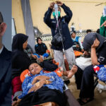 Left panel shows a close-up of a man in a dark suit and glasses speaking or being interviewed. Right panel depicts a makeshift clinic scene with people receiving medical care, some lying on stretchers or chairs, and others assisting with IV drips and medical supplies.