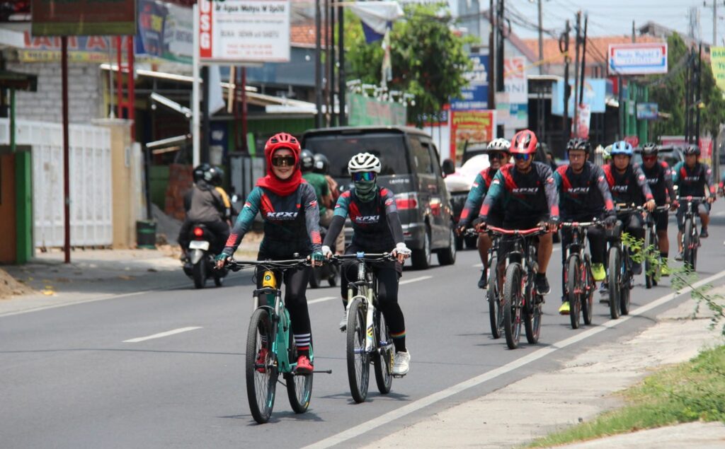 FB_IMG_1783211653236 - Mabur.co Group of cyclists riding on a city street, wearing helmets and matching jerseys.