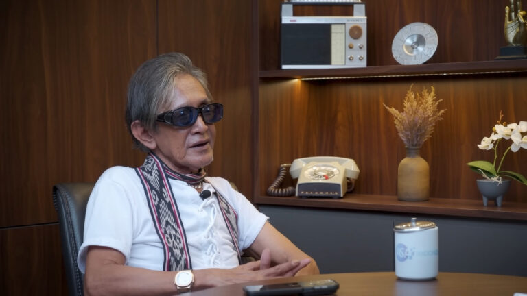 Ferry Latuhihin by Abraham Samad Speak Up FIXX - Mabur.co Older man with sunglasses sits at a desk in a wood-paneled office, talking during an interview.