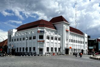 White multi-story bank building with red-tiled roof and BNI signs along a curved street.