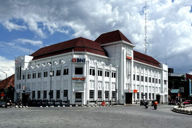 White multi-story bank building with red-tiled roof and BNI signs along a curved street.