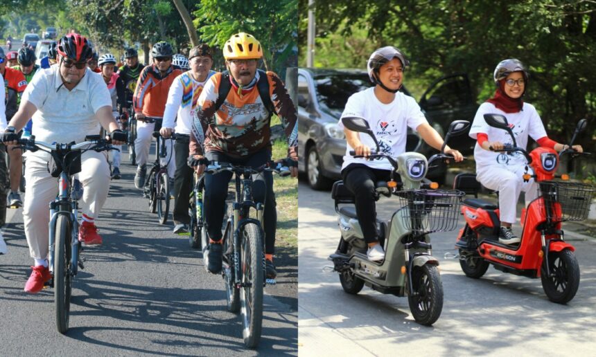 A large group of cyclists wearing helmets ride together on a sunny street; front riders in casual shirts and colorful jerseys.