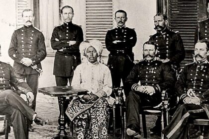 Group of uniformed military officers surrounding a central seated African woman in a turban and patterned dress; a colonial-era portrait.