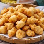 Pile of crispy golden chicken nuggets in a paper-lined wicker basket.