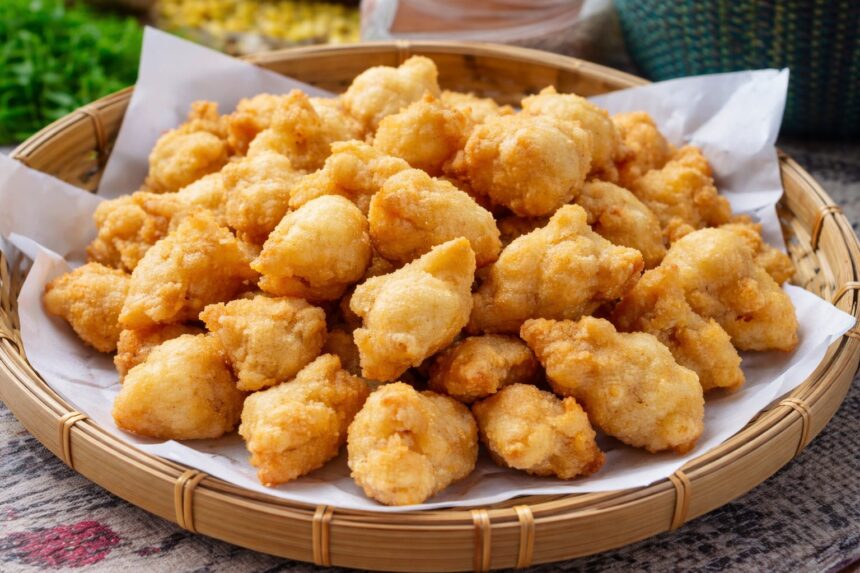 Pile of crispy golden chicken nuggets in a paper-lined wicker basket.