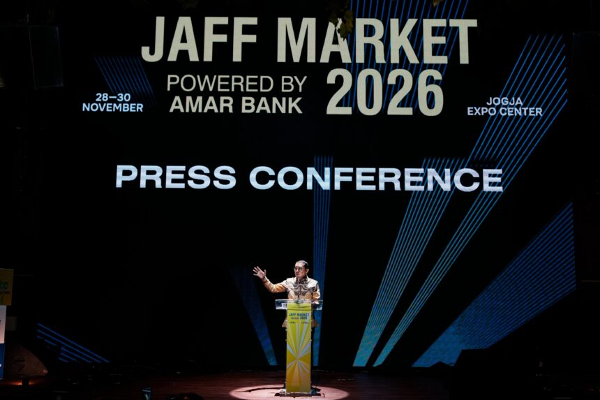 Speaker at a podium on a lit stage during a press conference with a large banner reading 'JAFF MARKET 2026' and 'POWERED BY AMAR BANK' in the background.