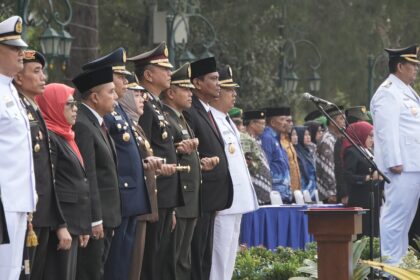 Line of uniformed officials and civilians standing at a formal ceremony behind a podium and microphones.