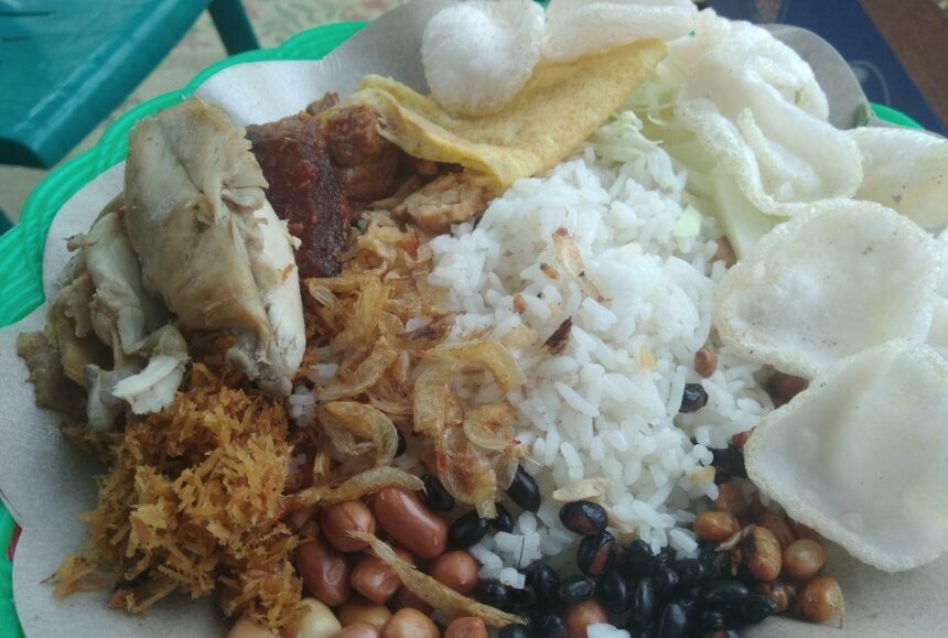 Plate with white rice, fried chicken, peanuts, fried onions, beans, and prawn crackers; a traditional mixed Malaysian nasi lemak style dish.