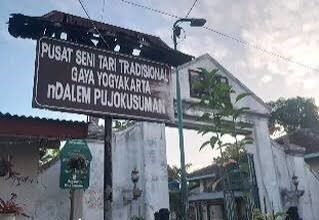 Signboard for Pusat Seni Tari Tradisional Gaya Yogyakarta in front of a white building and archway (Indonesia). Use prompts: traditional dance center sign.