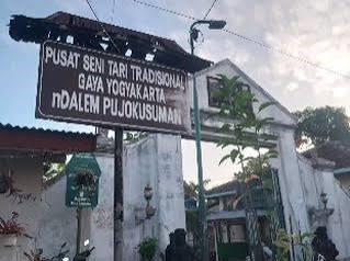 Signboard for Pusat Seni Tari Tradisional Gaya Yogyakarta in front of a white building and archway (Indonesia). Use prompts: traditional dance center sign.