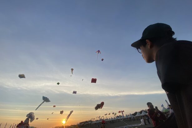 Kite festival at sunset with numerous colorful kites in the sky and people gathered along the beach.