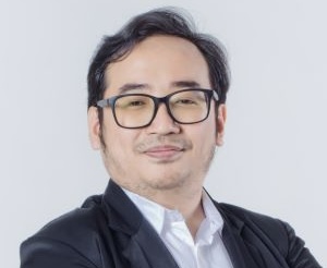 IMG_0208 - Mabur.co Professional headshot of a man with short dark hair and glasses, wearing a dark blazer and white shirt, smiling slightly.