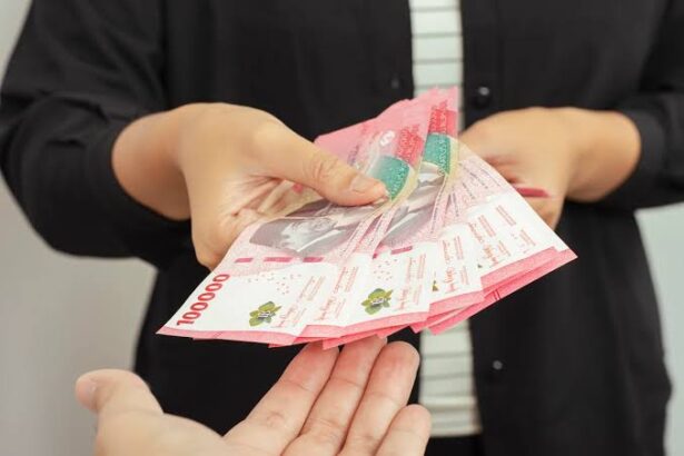 Two hands exchanging a fan of pink banknotes, cash transfer between people.