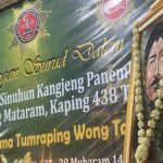 Ceremonial banner with Indonesian text, a star badge, and a portrait framed by a flower garland.