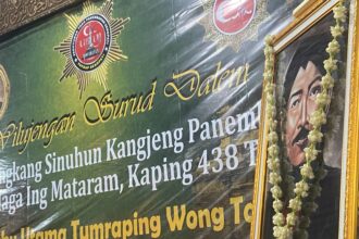 Ceremonial banner with Indonesian text, a star badge, and a portrait framed by a flower garland.